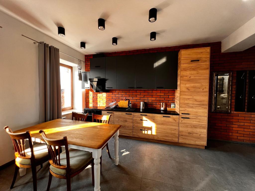 una cucina con tavolo in legno, sedie e bancone di Apartamenty na Maja -1- a Skierniewice