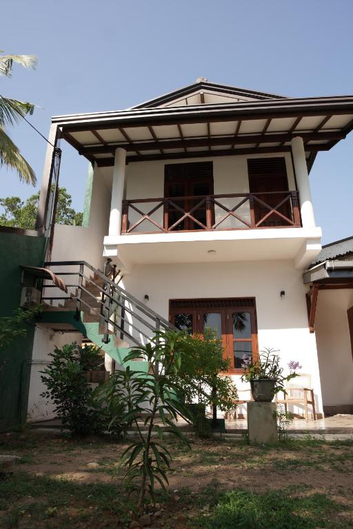 a white house with a balcony and stairs at Surf Nest Hiriketiya in Dickwella