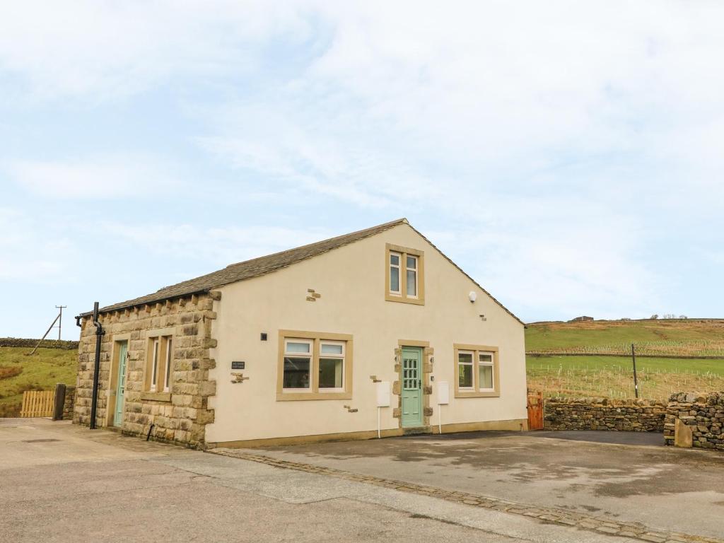 a stone cottage with a green door in a field at Meadow Cottage in Keighley