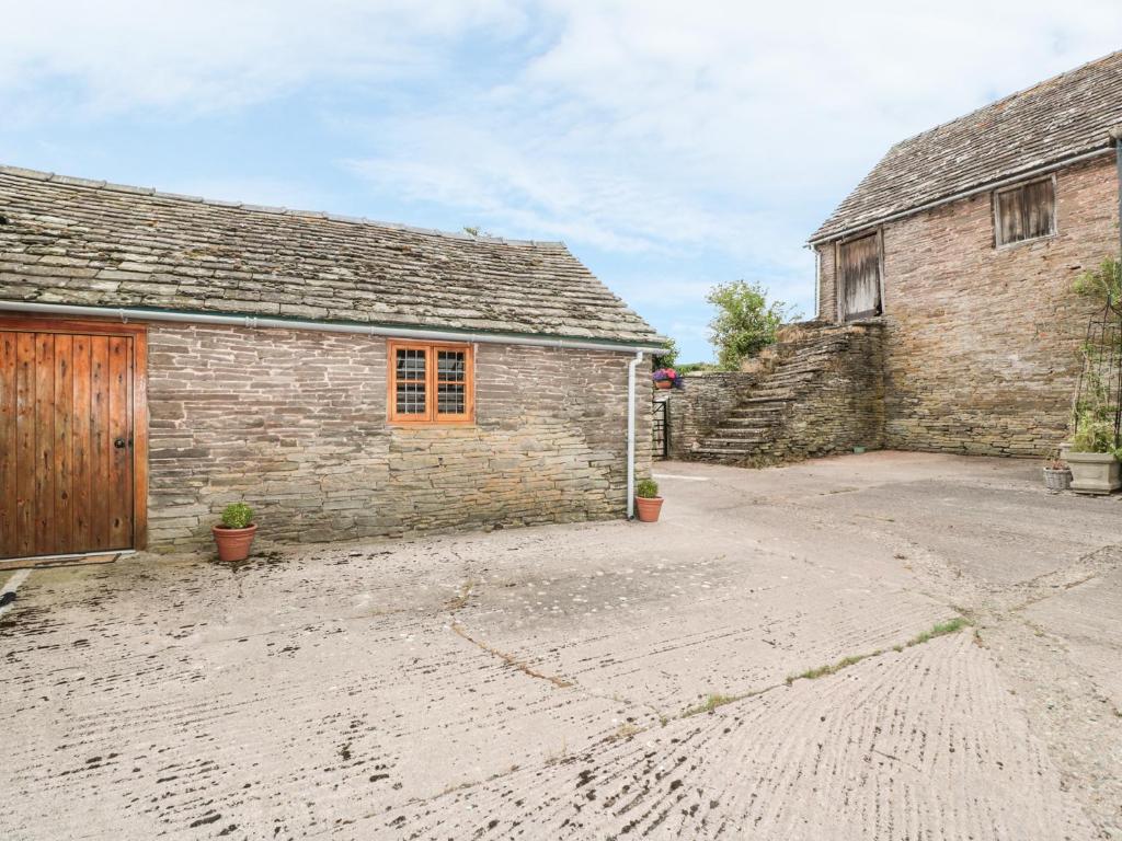 an old stone barn with a driveway in front of it at The Cow Cott in Peterchurch