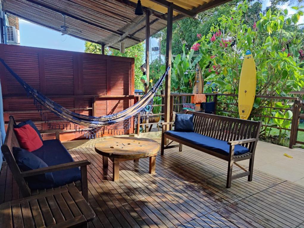 a porch with a hammock and a table and a surfboard at Tiny House Noronha in Fernando de Noronha