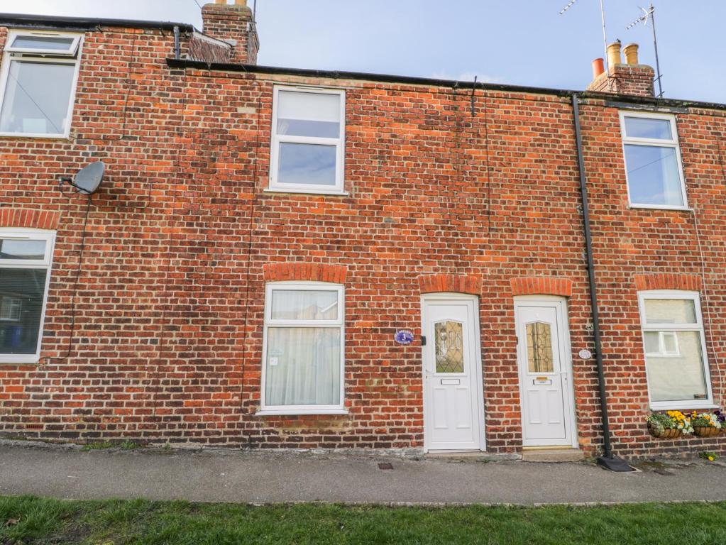 a brick building with white doors and windows at Sea Breakers Cottage in Filey