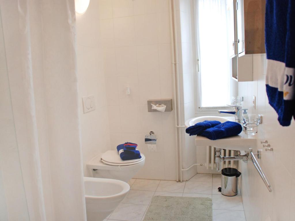 a white bathroom with a toilet and a sink at Holiday Home Casa Naima by Interhome in Breno
