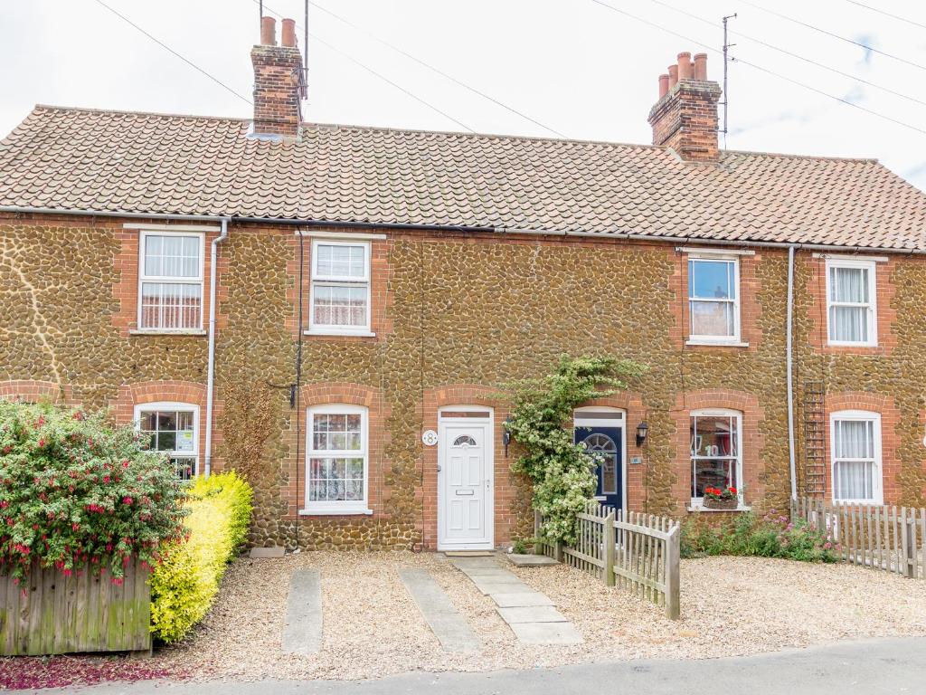 a brick house with a white door at Penny Cottage in Heacham