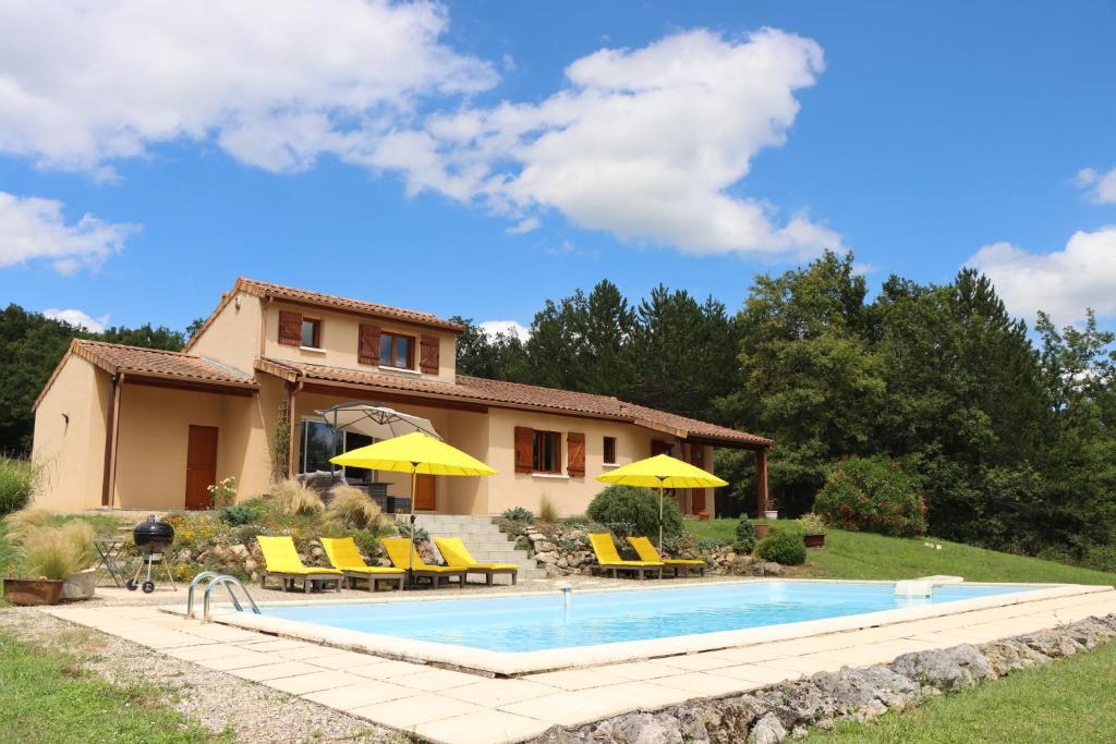 una piscina frente a una casa con sillas y sombrillas en Villa Padam, en Monsac