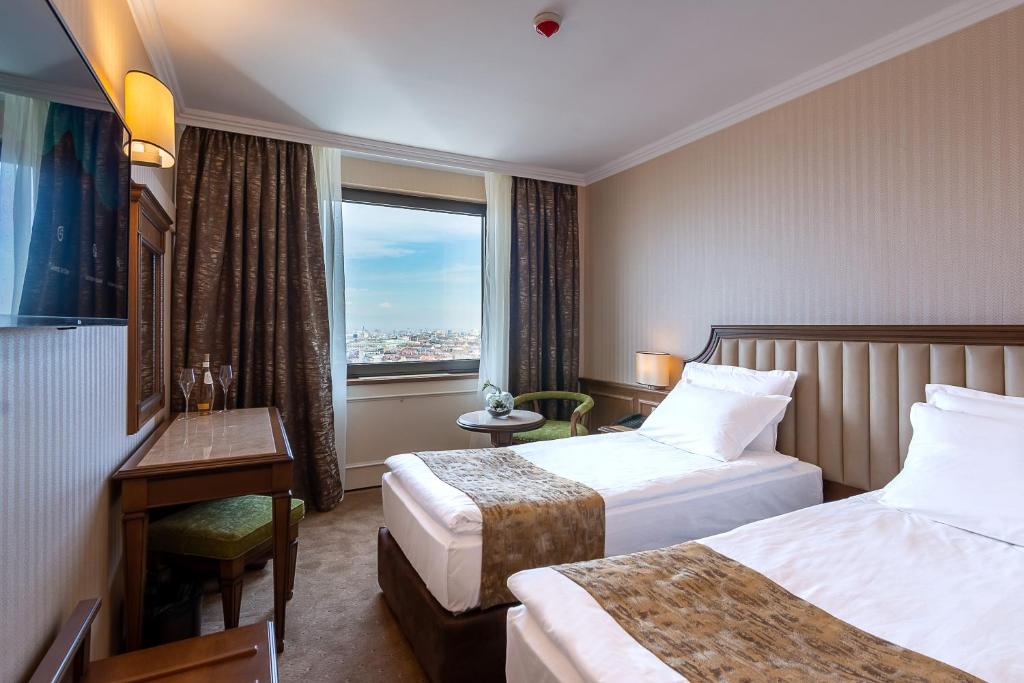 a hotel room with two beds and a window at Astoria Grand Hotel in Sofia
