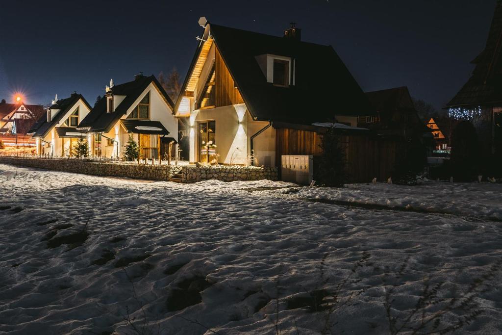 una calle nevada frente a las casas por la noche en Osada Białka Tatrzańska - apartamenty & domki z ogrodem dla rodzin Odkryj-Bialke, en Białka Tatrzanska