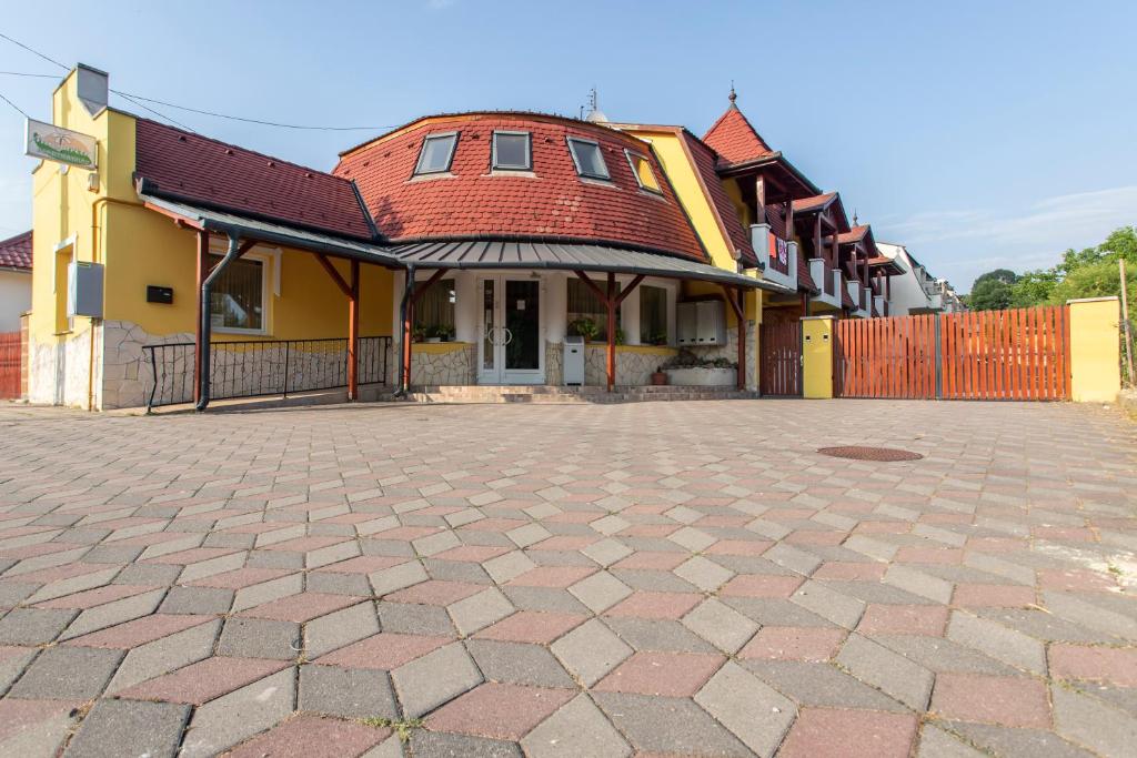 uma casa amarela com um telhado vermelho e uma entrada em Margaréta Apartman és Üdülőház em Bogács