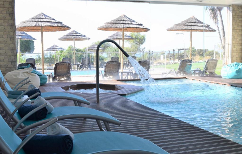 a swimming pool with a fountain and chairs and umbrellas at Vila Alba Resort in Carvoeiro