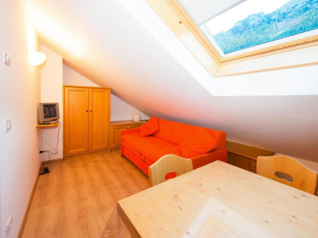 uma sala de estar com um sofá laranja e uma clarabóia em Apartment Enrosadira-7 by Interhome em Alba di Canazei