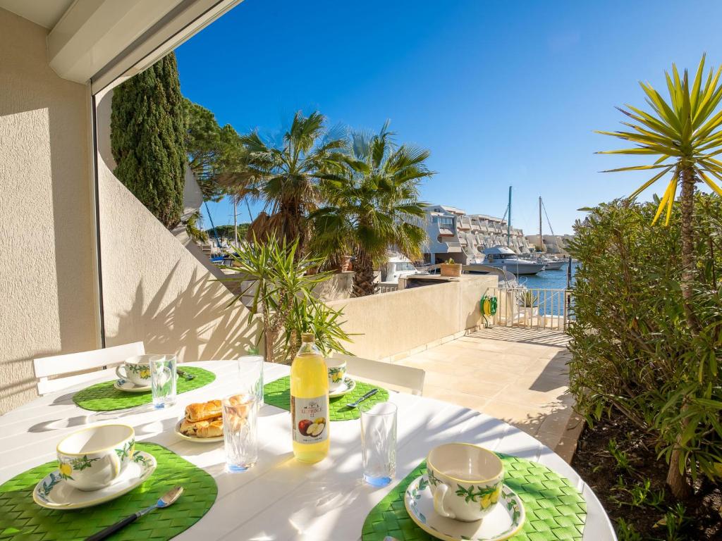 a table with two cups and plates of food on a balcony at Holiday Home Hélios by Interhome in Le Grau-du-Roi