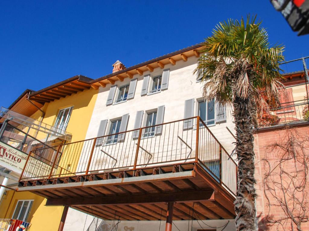 a yellow and white building with a palm tree at Apartment Al Puntil by Interhome in Gandria