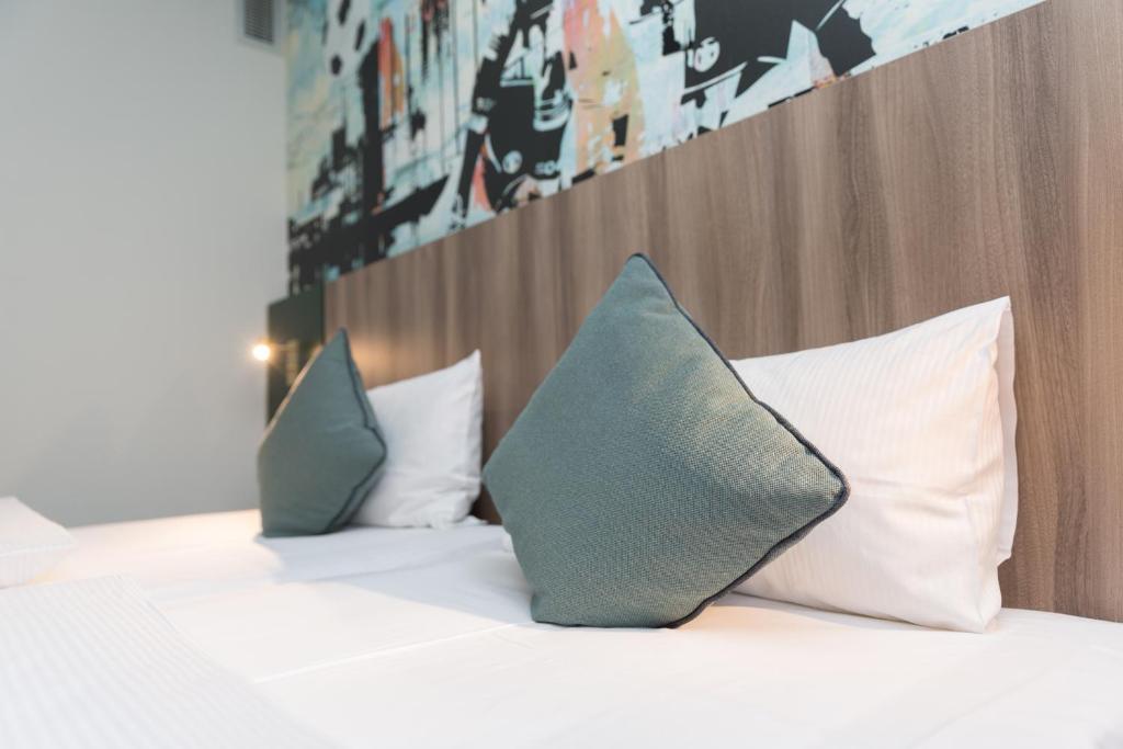 
a bed with pillows and pillows on it at Good Morning Gelsenkirchen City in Gelsenkirchen
