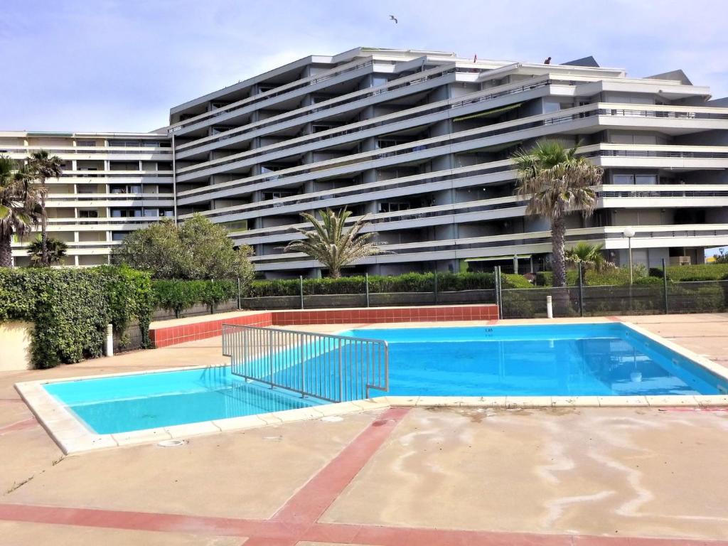an empty swimming pool in front of a large building at Apartment Grand Sud-16 by Interhome in Canet-en-Roussillon