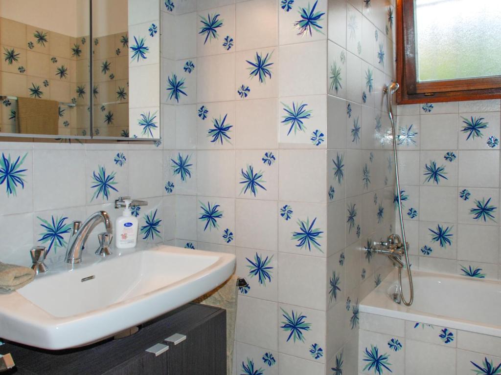 a bathroom with blue and white tiles with a sink and a tub at Apartment App- Castausio 26 by Interhome in Lugano