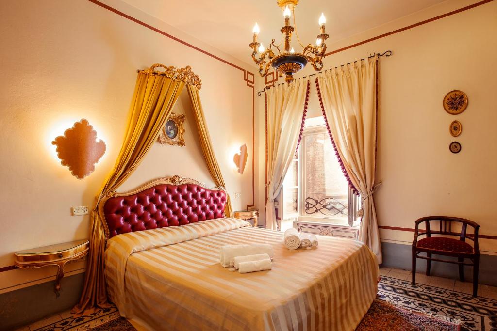 Schlafzimmer mit einem großen Bett mit rotem Kopfteil in der Unterkunft Palazzo Barbini Dimora Storica in Castiglione del Lago