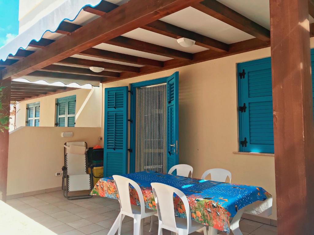patio ze stołem, krzesłami i niebieskimi okiennicami w obiekcie appartamento residence via giardini Acquamarina w mieście San Vito lo Capo