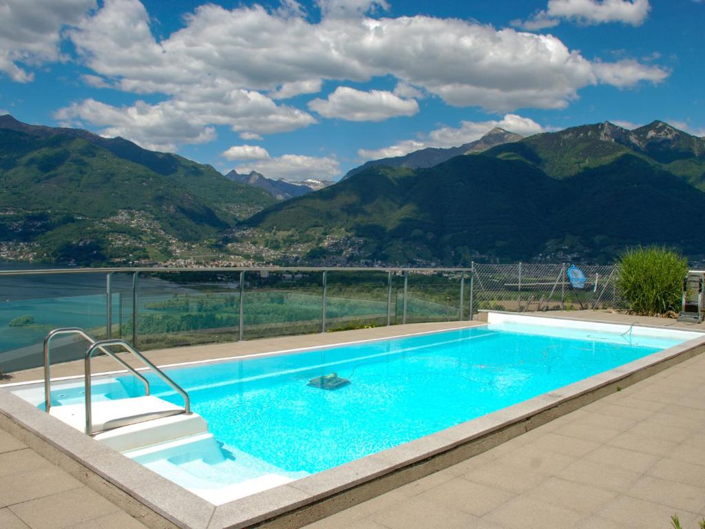 a swimming pool with mountains in the background at Apartment Bella Vista by Interhome in Magadino