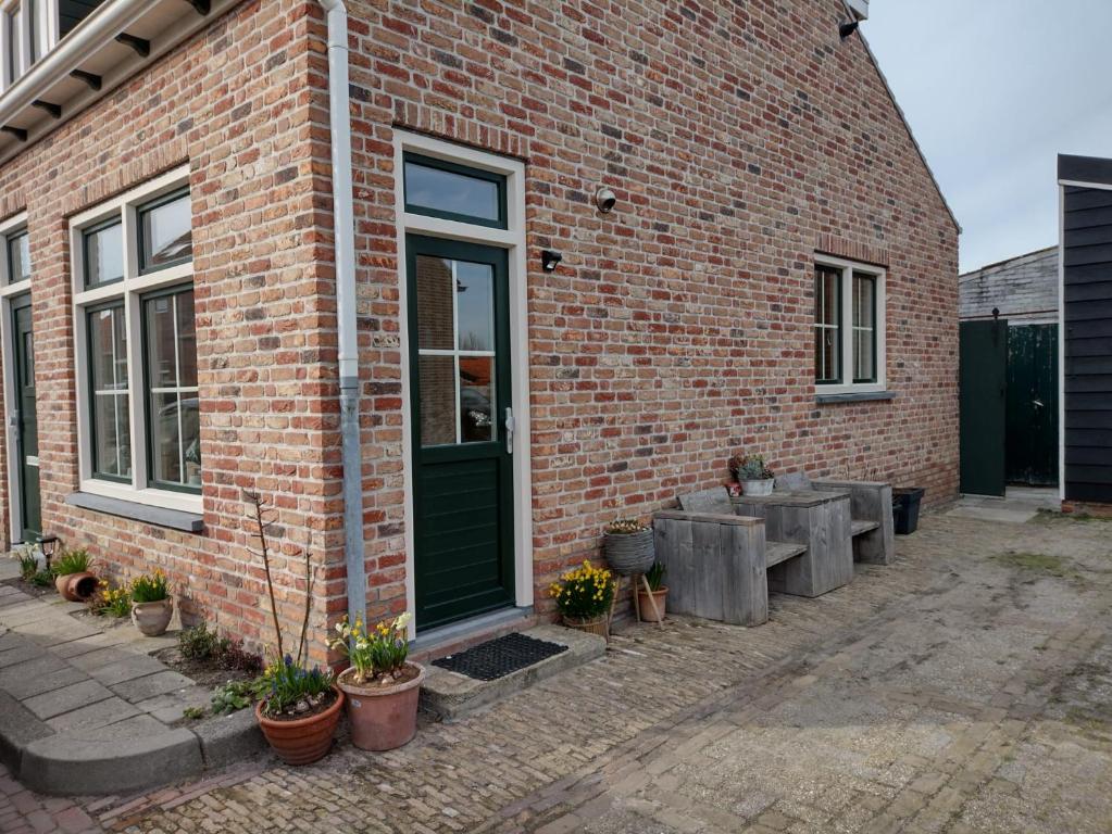 a brick building with a green door and some potted plants at Hout 25 in Westkapelle