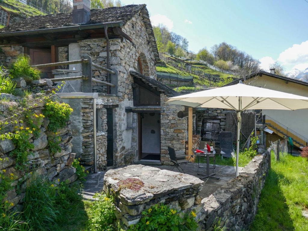 een stenen huis met een tafel en een paraplu bij Holiday Home Scateto 66 by Interhome in Malvaglia