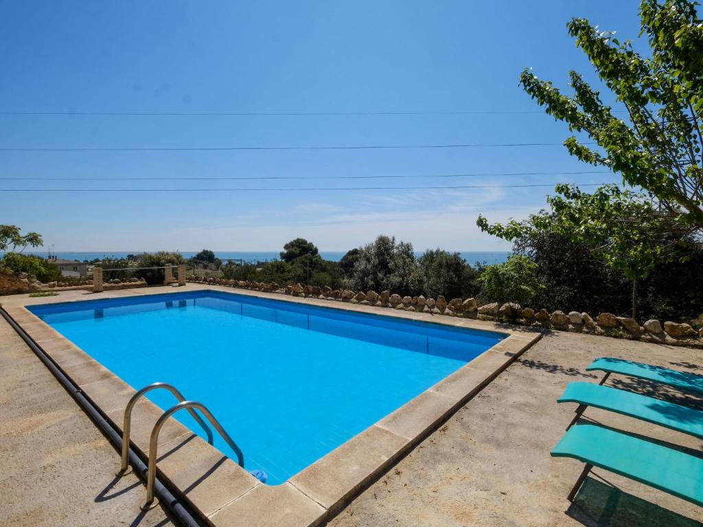 uma grande piscina azul com duas cadeiras azuis em Holiday Home Pino by Interhome em Les Cases d'Alcanar