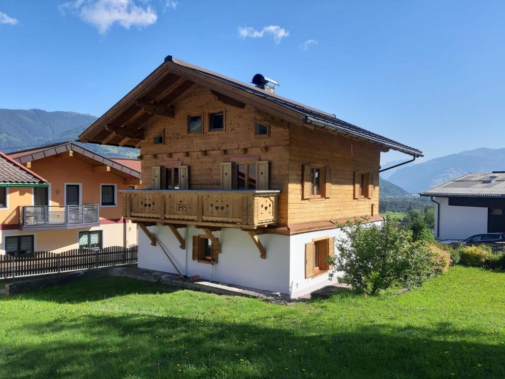 een houten huis met een balkon op een groen veld bij Holiday Home Haus Weickl by Interhome in Kaprun