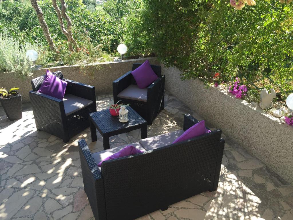 a patio with chairs and tables with purple pillows at Apartments Tamara in Orebić
