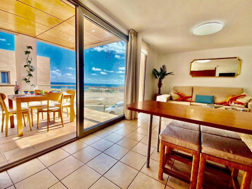 a living room with a couch and a table with a view of the ocean at Suite del Mar Playa Esquinzo 1 Jandia Fuerteventura in Playa Jandia