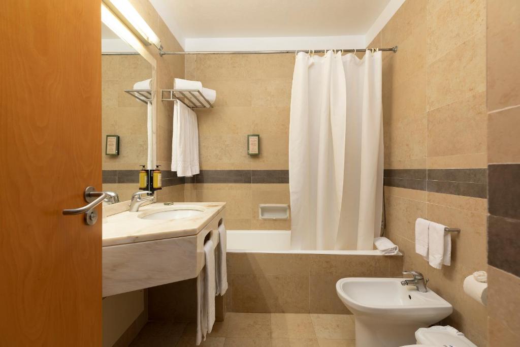 a bathroom with a sink and a toilet and a tub at Interpass Vau Hotel Apartamentos in Portimão
