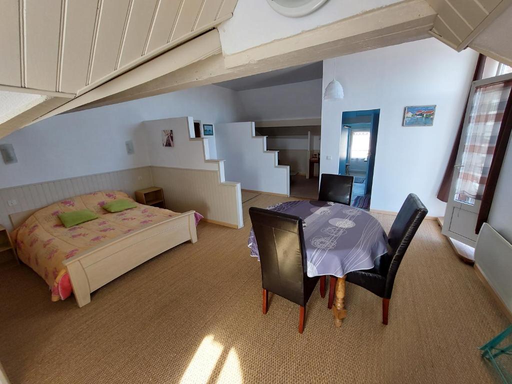 1 dormitorio con 1 cama, mesa y sillas en Chambres d'Hôtes L'Insulaire en Saint-Denis-dʼOléron