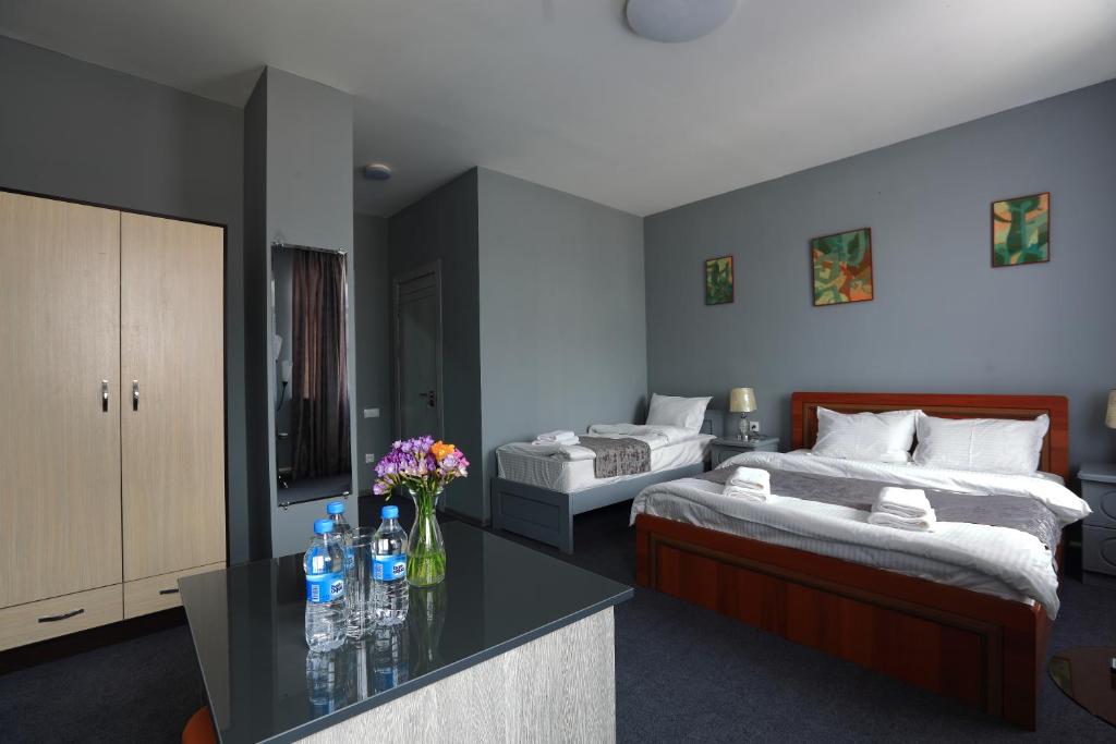 a bedroom with two beds and a table with flowers at Hotel Evita Tashkent in Tashkent
