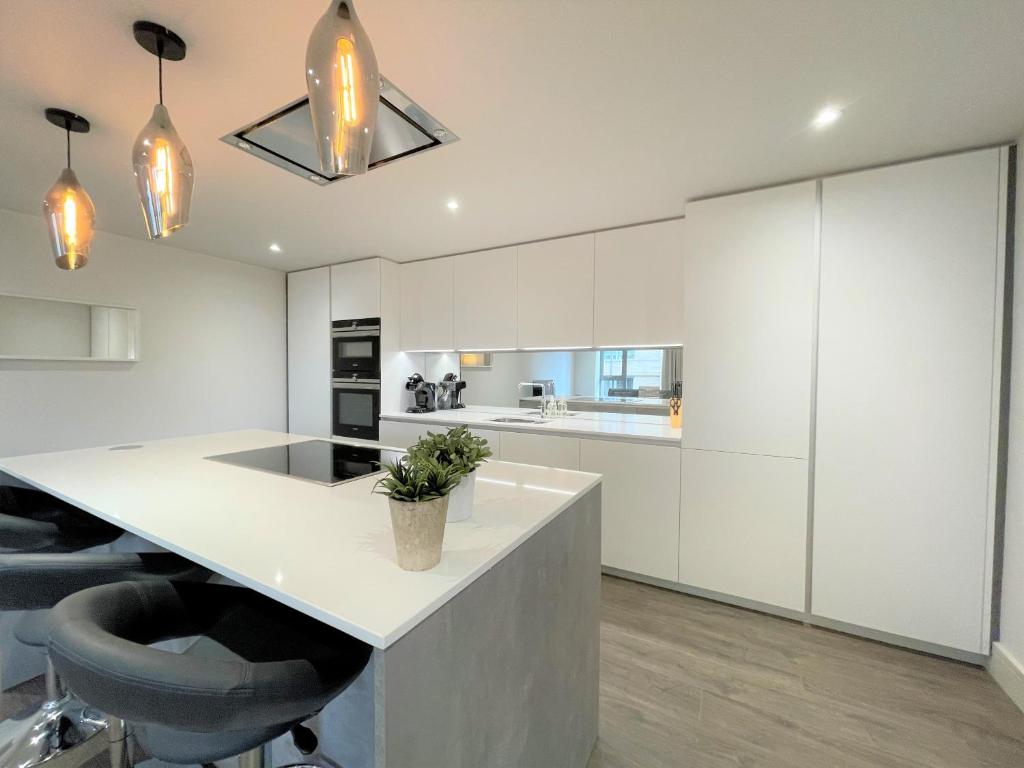 uma cozinha com armários brancos e uma grande ilha com cadeiras pretas em Spectacular 2 Bedroom Apartment in Great Location em Sheffield