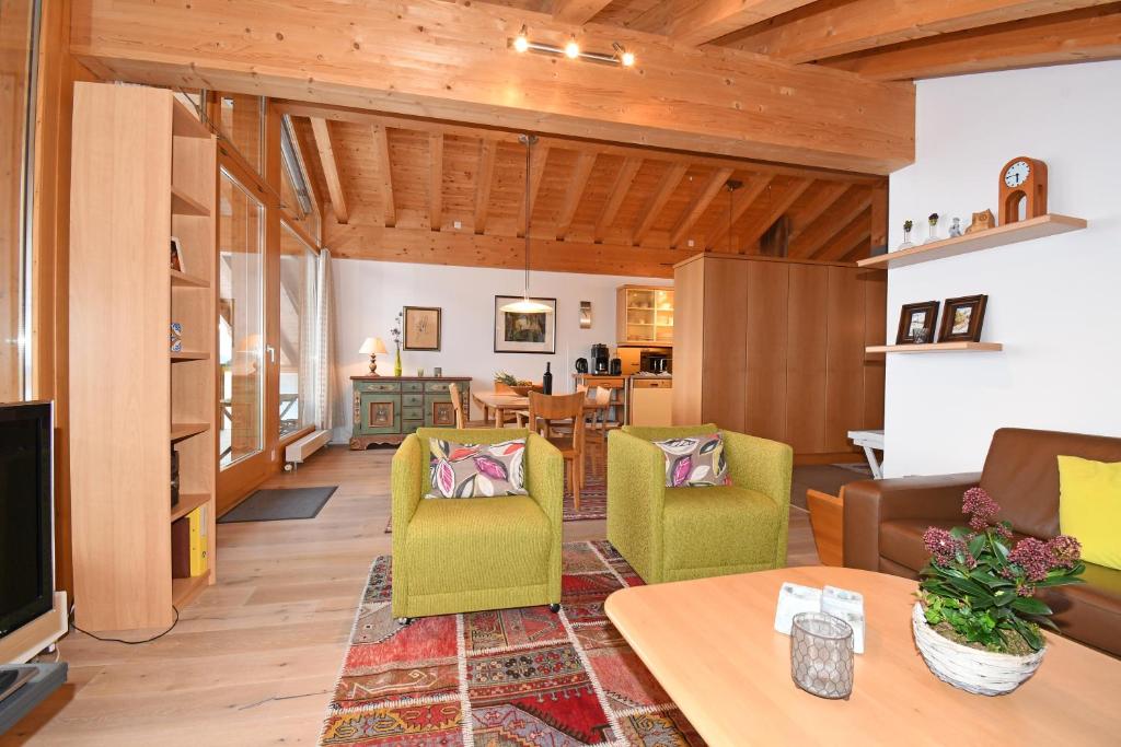 a living room with wooden ceilings and green chairs at Emilio Dachgeschoss in Riederalp