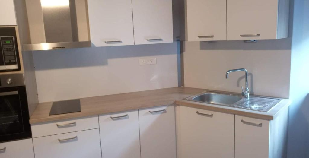 a kitchen with white cabinets and a sink at Le puits de Mine d'appart in Cransac