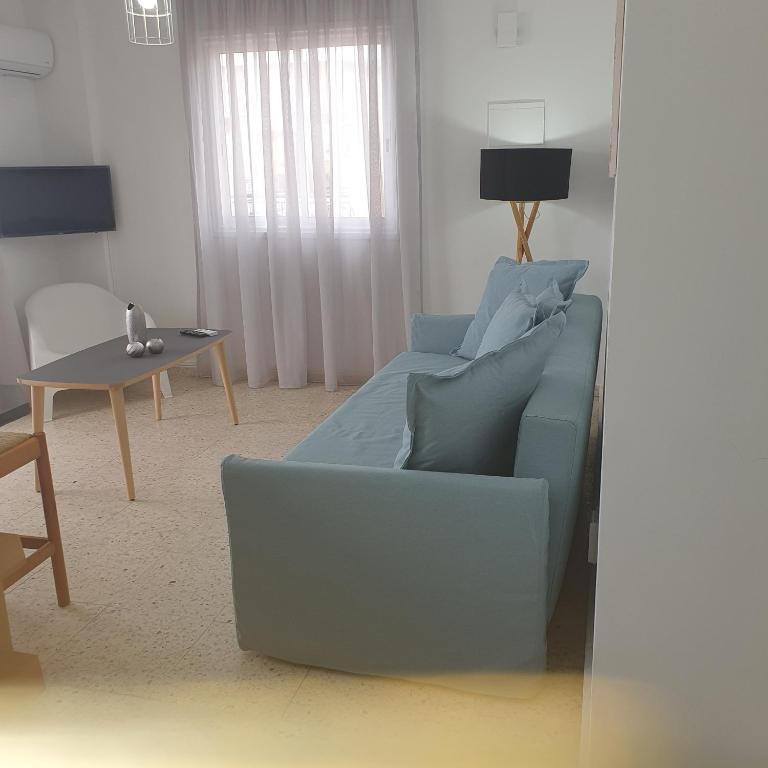 a living room with a blue couch and a table at G&E Harbour Apartments in Lachi