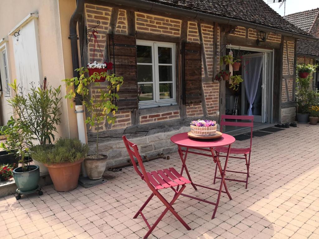 una mesa roja y sillas frente a una casa en Gîte de la Ferme de la Terve, en Bruailles