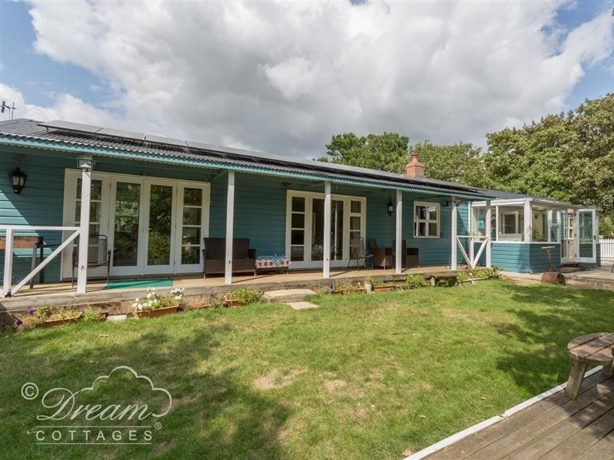 a blue house with a yard in front of it at Harbour View Bungalow in Weymouth