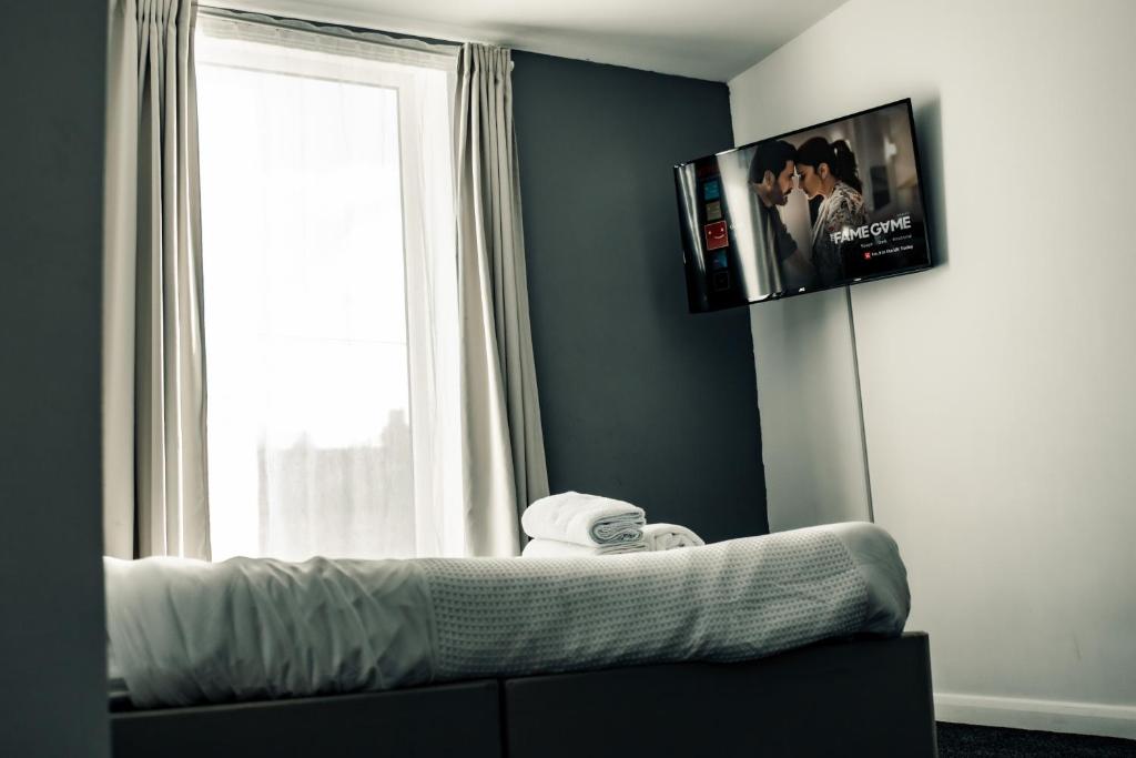 1 dormitorio con TV en la pared y ventana en Dealhouse Apartments 10, en Huddersfield