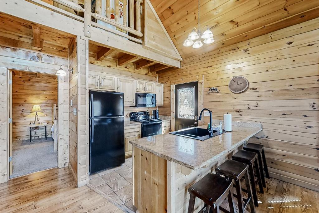 a kitchen with a black refrigerator and wooden walls at Parton Ways in Pigeon Forge