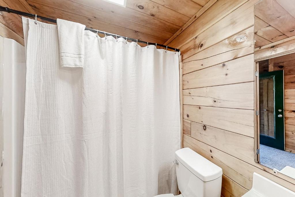 a white shower curtain in a bathroom with wooden walls at Parton Ways in Pigeon Forge
