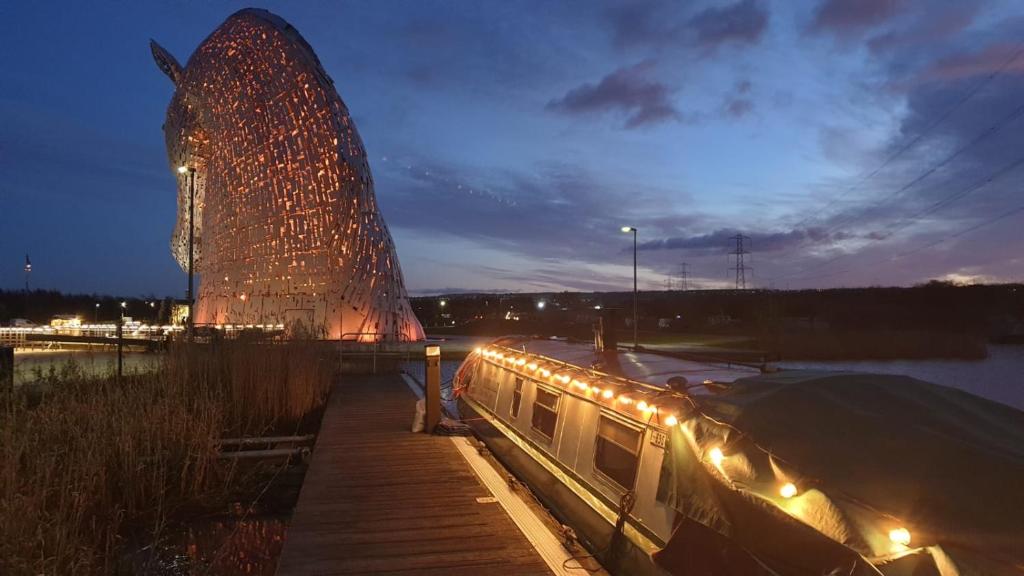 a boat parked next to a building at night at NEW 2022! Fixed stay characterful narrowboat at the Kelpies, Marigold Sunset in Falkirk