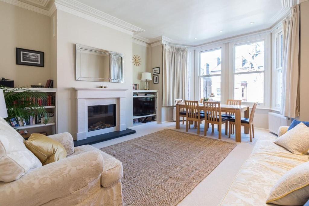 a living room with a table and a fireplace at Homely 2 Bedroom Victorian Apartment in Hampstead in London