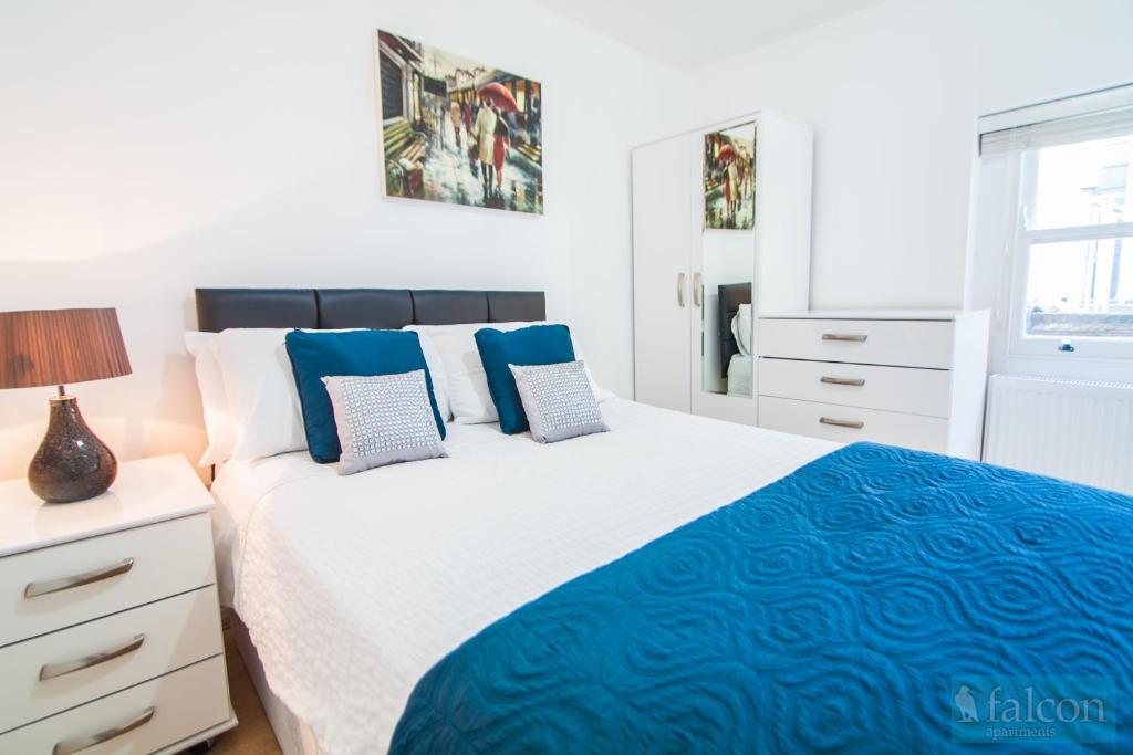 a bedroom with a large bed with blue pillows at Maple Street Apartments in London