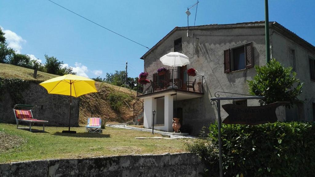 a house with a balcony and a yellow umbrella at Oasi delle Gazze in Genga