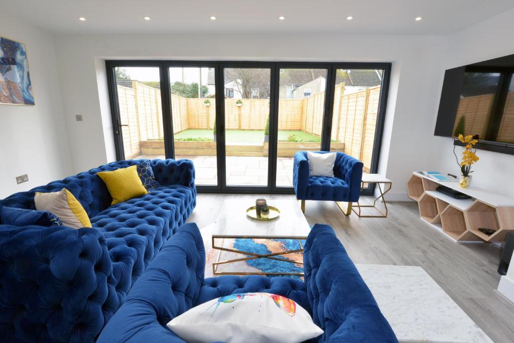 a living room with blue couches and a large window at Outstanding modernised 3/4 double bedroomed house in Littlehampton