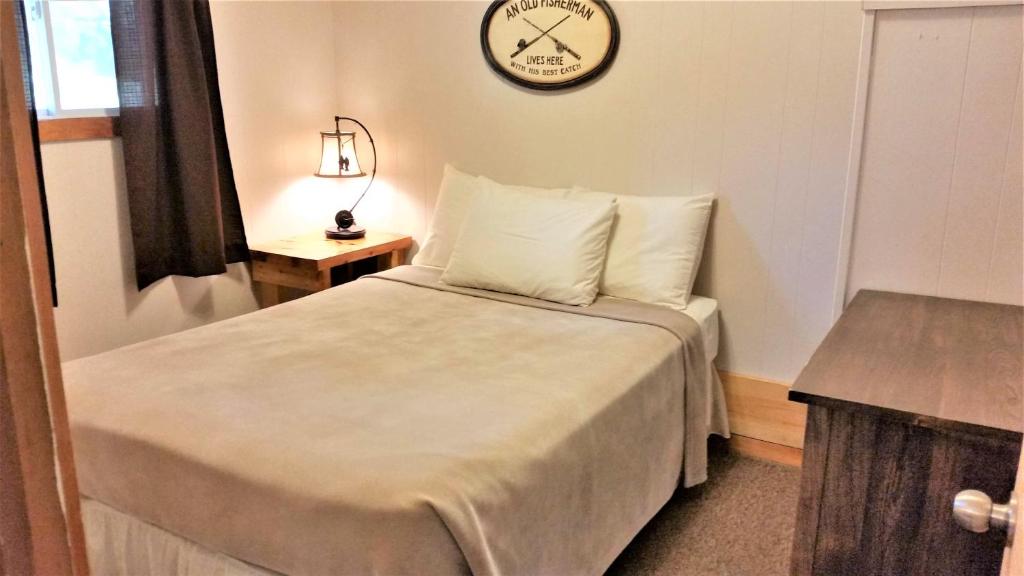 Logging Chain Lodge Cottage Resort في Dwight: غرفة صغيرة بها سرير وساعة على الحائط