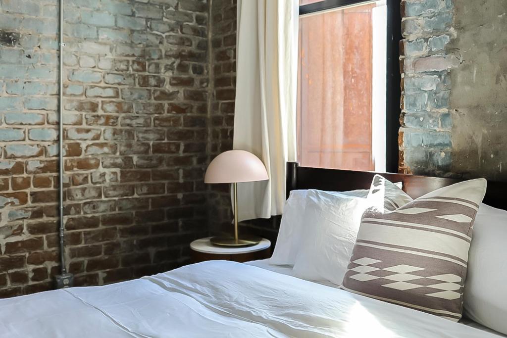 a bedroom with a bed and a brick wall at The Grant by Black Swan in Savannah