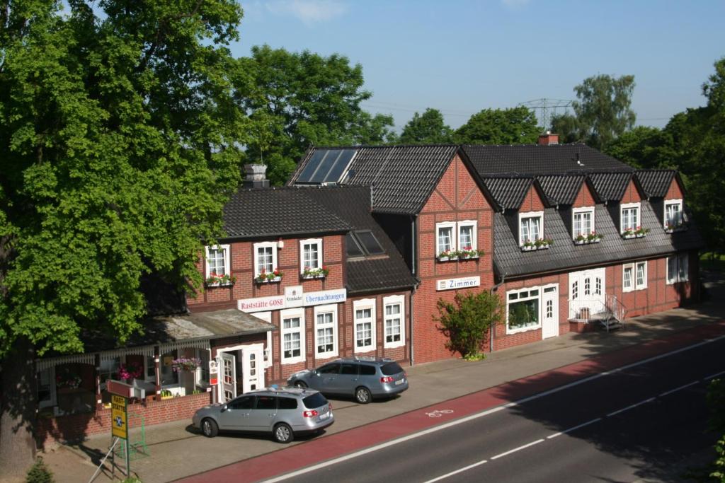 uma fila de casas de tijolos com carros estacionados na rua em Hotel Gasthof Gose em Ziegenhagen
