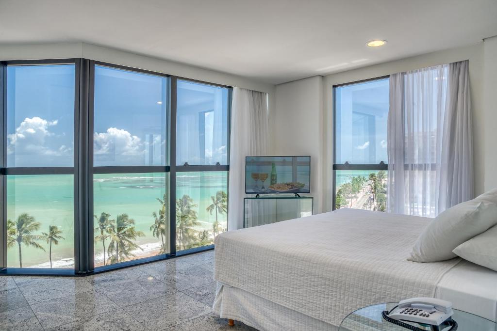 a bedroom with a bed and views of the ocean at Hotel Brisa Tower Maceió in Maceió
