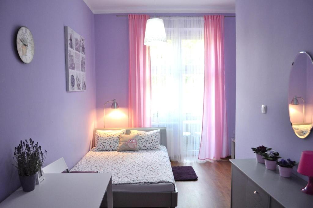 1 dormitorio con 1 cama y una ventana con cortinas rosas en Happy House Hostel, en Poznan